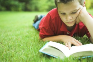 jongen leest op gras